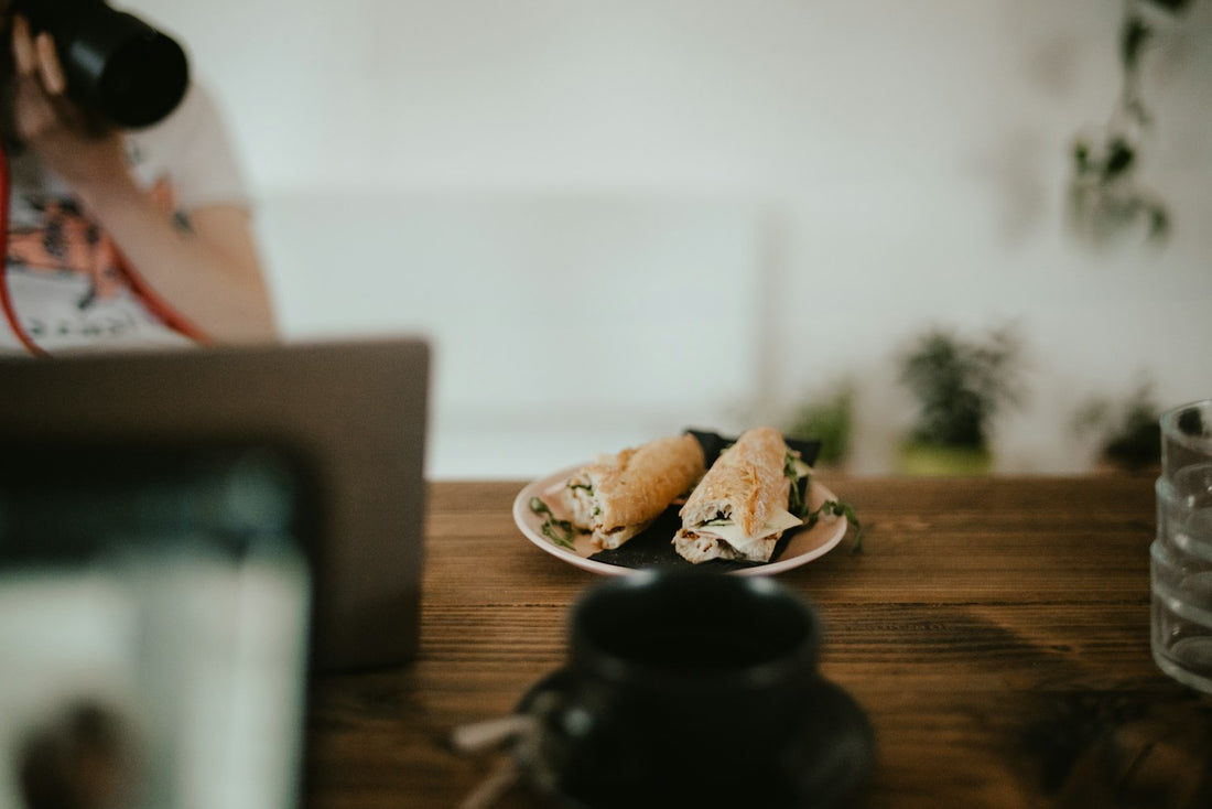 Lunch wraps on a plate beside a laptop on a wooden desk, eating at work during a long office day