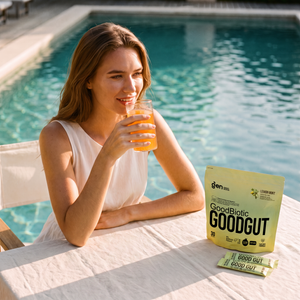 Woman by a pool drinking GoodGut Pineapple, pack and sachets on the table