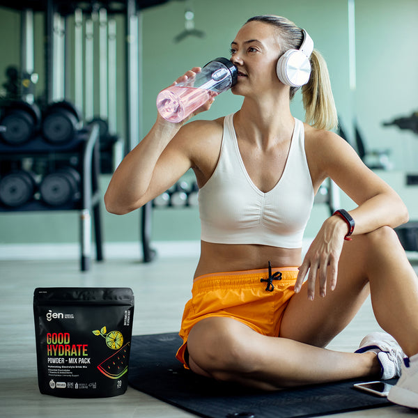 Woman at the gym drinking GoodHydrate after a workout, Mix Pack on the floor